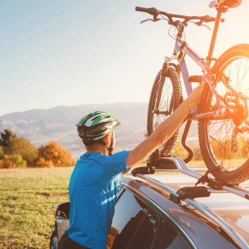 Mountain biker man take of his bike from the car roof